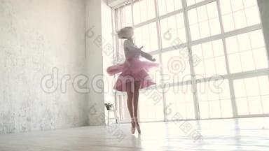 芭蕾舞演员在一扇明亮的大窗户的背景下动态地旋转。 穿着古典芭蕾舞裙和